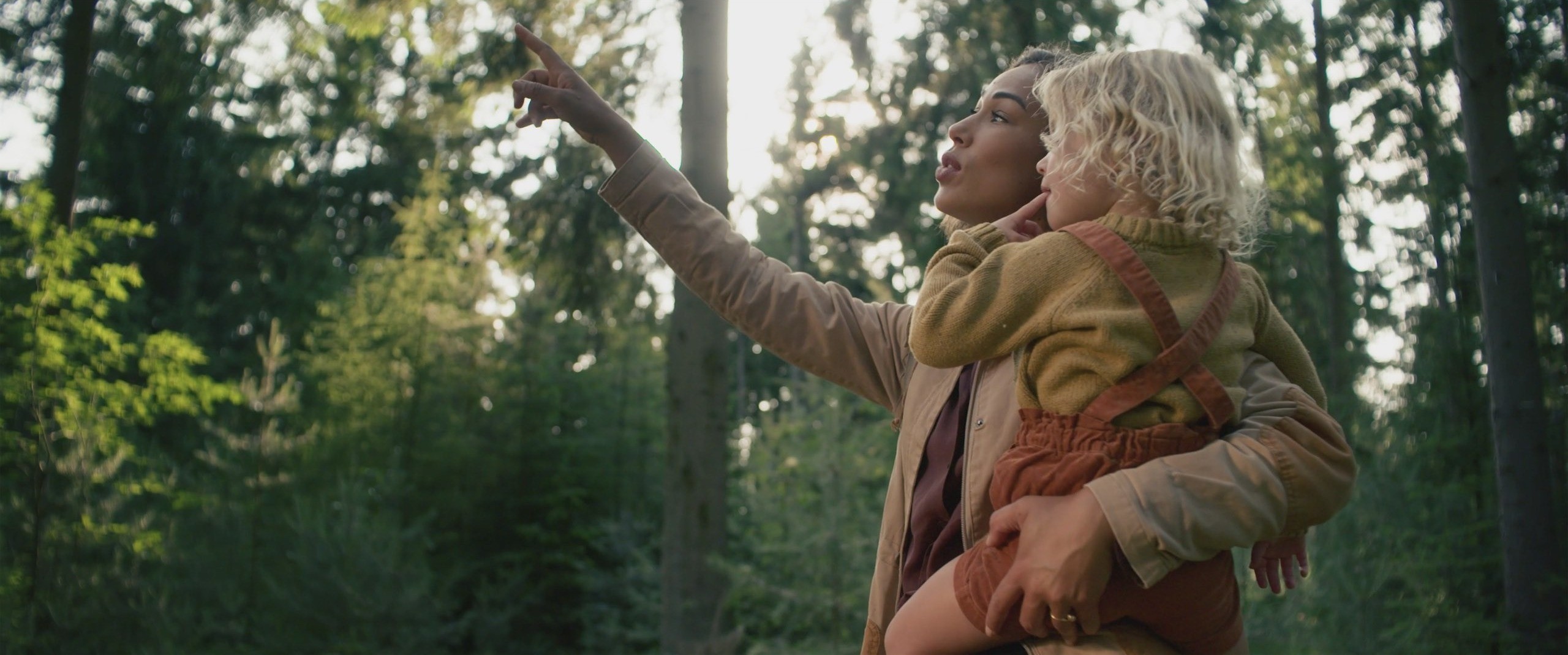 This image shows a mother carrying her dauther in the woods and pointing at something that they see 2.jpg